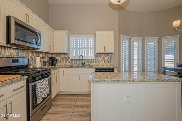 kitchen with appliances with stainless steel finishes, plenty of natural light, white cabinetry, and sink