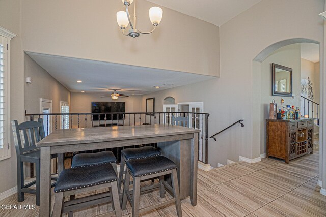 kitchen featuring ceiling fan with notable chandelier, a kitchen breakfast bar, and tile patterned floors