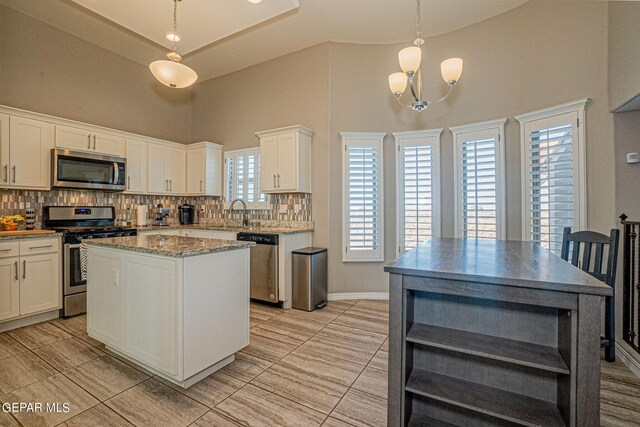 kitchen featuring decorative light fixtures, appliances with stainless steel finishes, a center island, and a healthy amount of sunlight