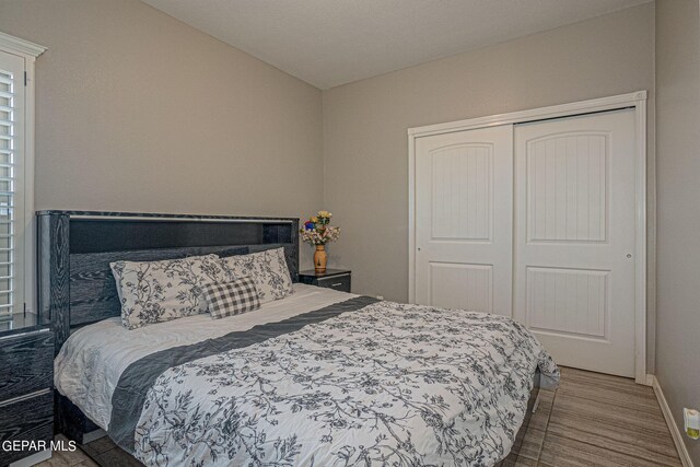 bedroom featuring hardwood / wood-style flooring, lofted ceiling, and a closet