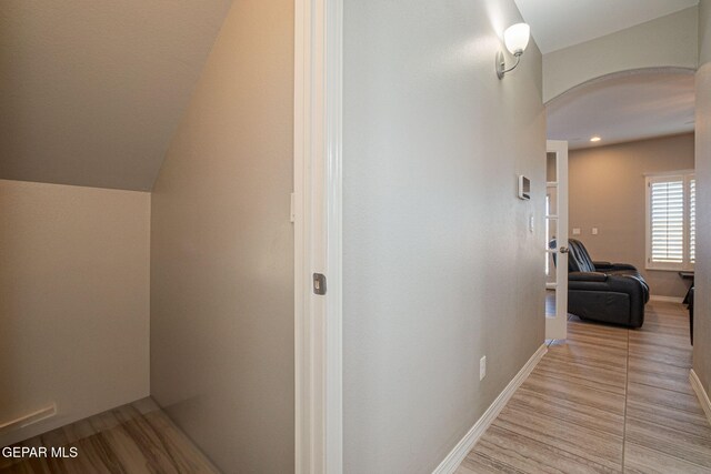 hall with light wood-type flooring and lofted ceiling