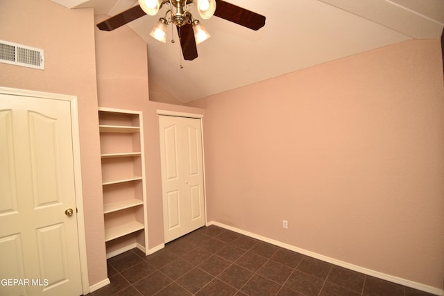 unfurnished bedroom with lofted ceiling, dark tile patterned flooring, and ceiling fan