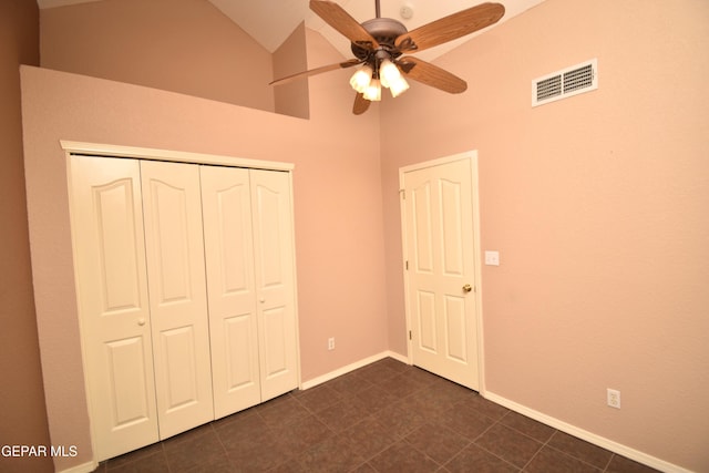 unfurnished bedroom with vaulted ceiling, dark tile patterned flooring, a closet, and ceiling fan