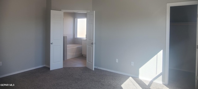 unfurnished bedroom with a closet and dark colored carpet