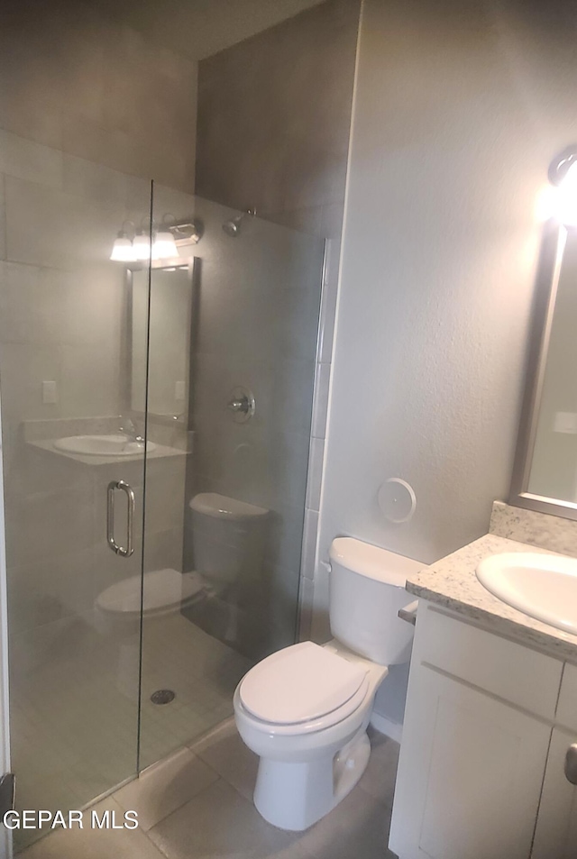 bathroom with tile patterned floors, vanity, a shower with door, and toilet