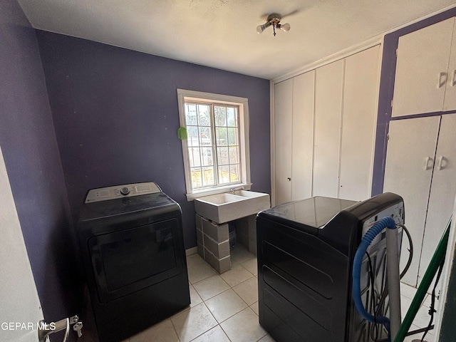 laundry area with washing machine and dryer and light tile patterned floors