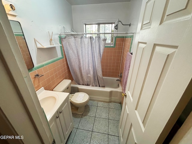 full bathroom with tile patterned floors, toilet, shower / bath combo with shower curtain, vanity, and tile walls