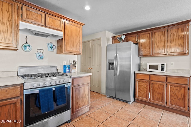 kitchen featuring a textured ceiling, appliances with stainless steel finishes, and light tile patterned floors