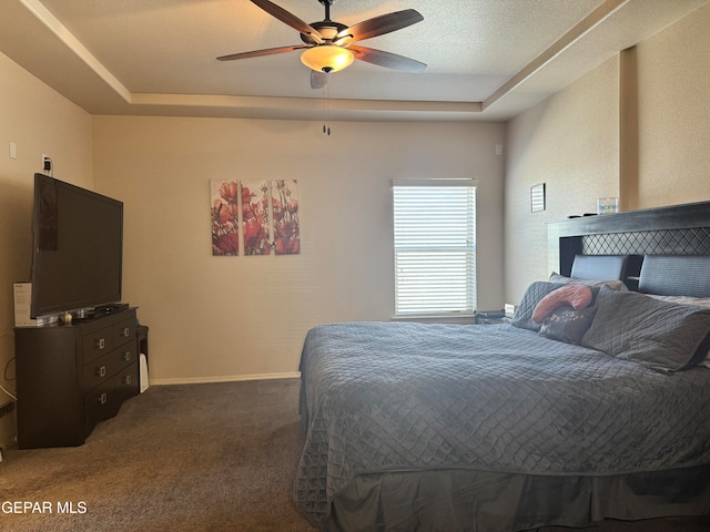 carpeted bedroom with a tray ceiling and ceiling fan