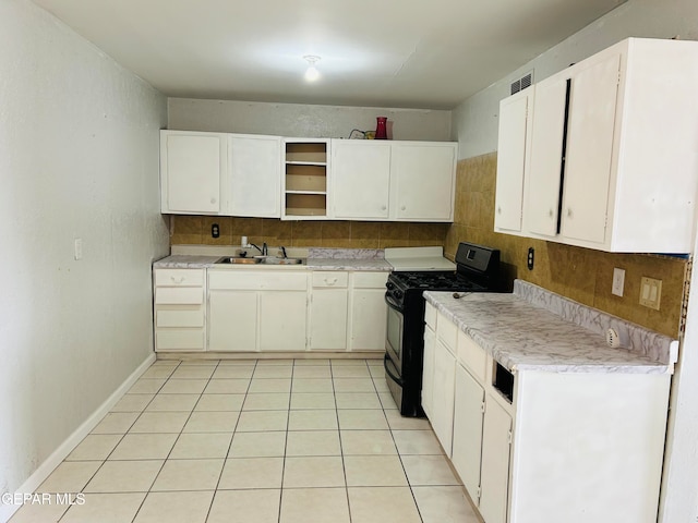 kitchen featuring light tile patterned flooring, black gas range oven, sink, and white cabinets