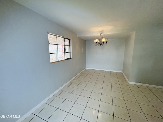 tiled spare room with an inviting chandelier