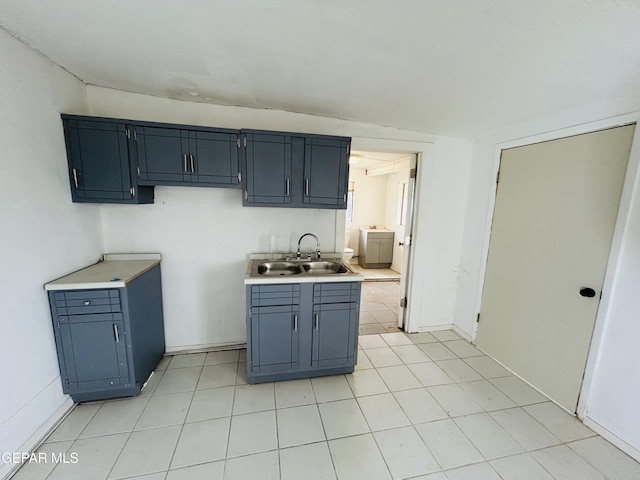 kitchen featuring sink, light tile patterned floors, and blue cabinetry