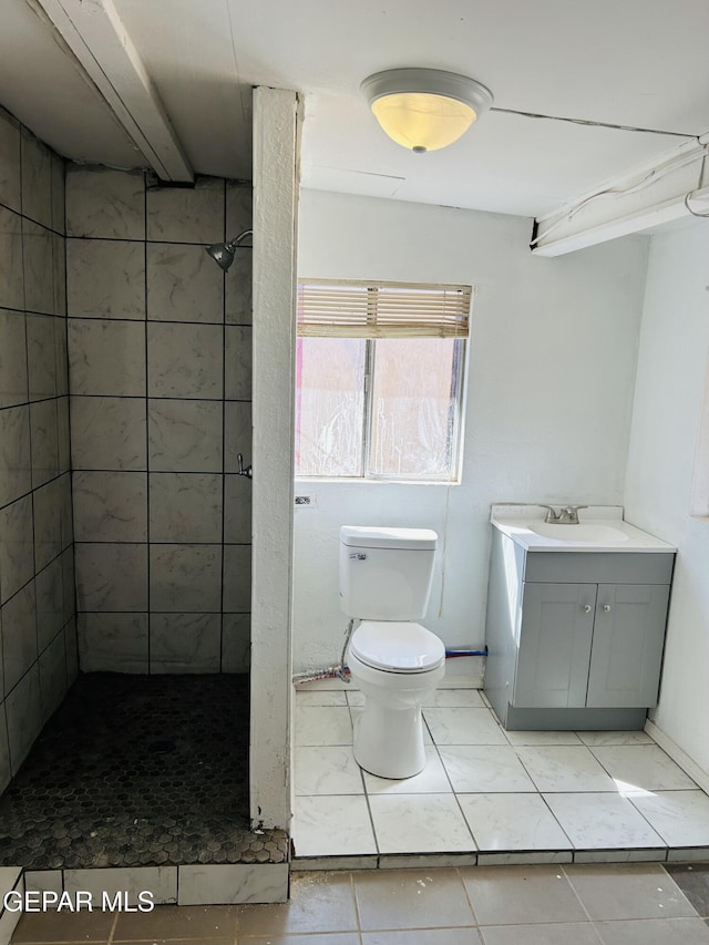 bathroom featuring tiled shower, vanity, and toilet