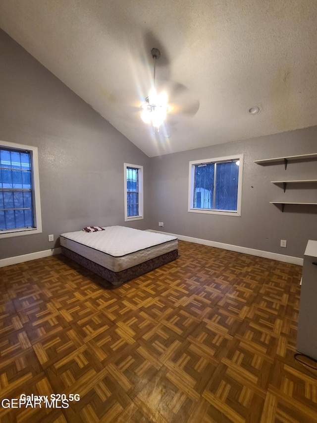 unfurnished bedroom with a textured ceiling, ceiling fan, dark parquet floors, and lofted ceiling