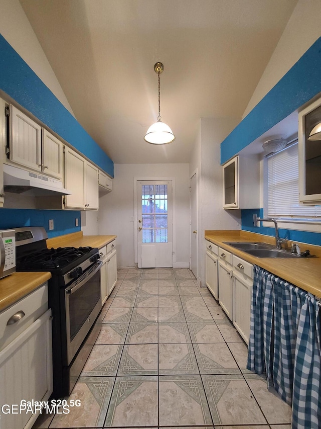 kitchen with stainless steel gas stove, sink, vaulted ceiling, decorative light fixtures, and white cabinets