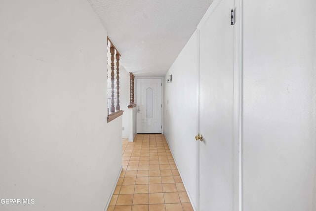 corridor featuring a textured ceiling and light tile patterned floors