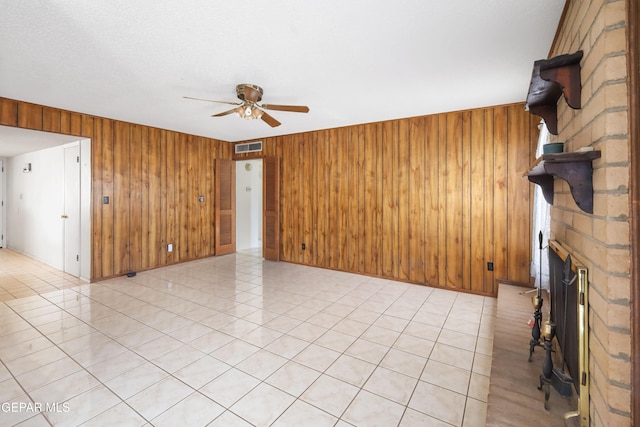 unfurnished living room featuring wood walls, light tile patterned flooring, a fireplace, and ceiling fan