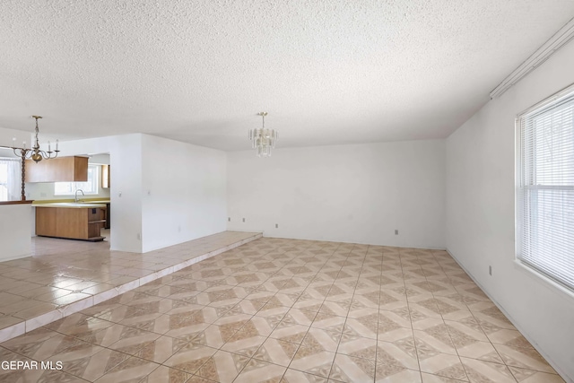 spare room featuring sink, an inviting chandelier, and a textured ceiling