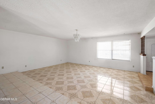 unfurnished room with a textured ceiling and a notable chandelier