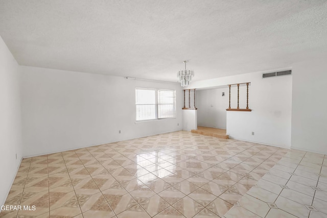 unfurnished room featuring an inviting chandelier and a textured ceiling