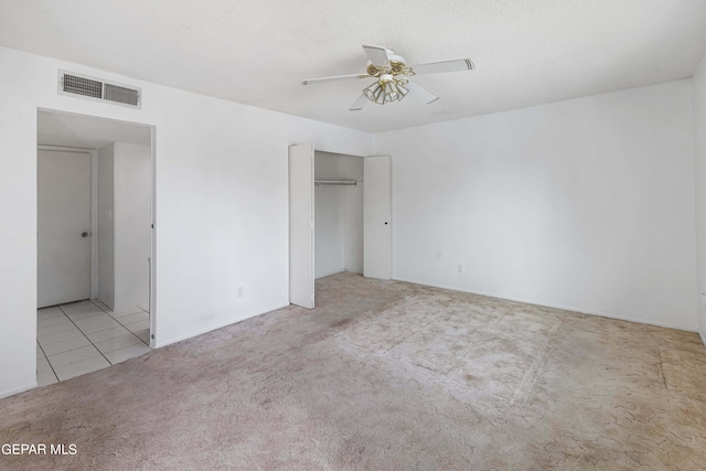 unfurnished bedroom with a textured ceiling, ceiling fan, a closet, and light colored carpet