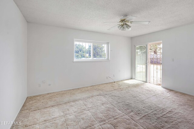 unfurnished room with ceiling fan, light colored carpet, and a textured ceiling