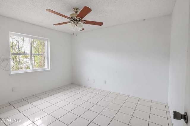 tiled empty room featuring ceiling fan and a textured ceiling