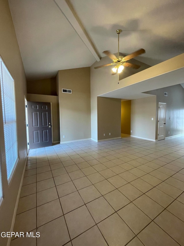 tiled spare room featuring ceiling fan, lofted ceiling with beams, and a wealth of natural light