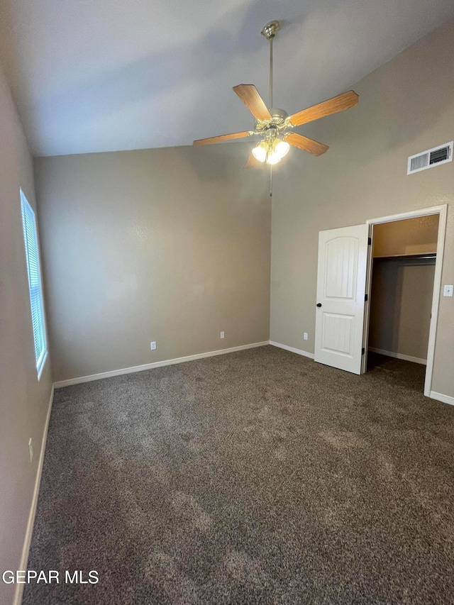 unfurnished bedroom with dark colored carpet, vaulted ceiling, and ceiling fan