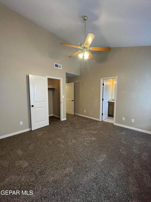 unfurnished bedroom with a spacious closet, ceiling fan, high vaulted ceiling, ensuite bathroom, and carpet