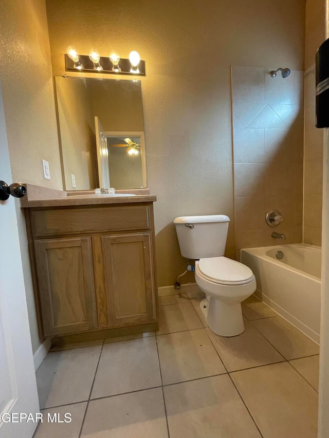 full bathroom with tiled shower / bath, tile patterned floors, vanity, and toilet