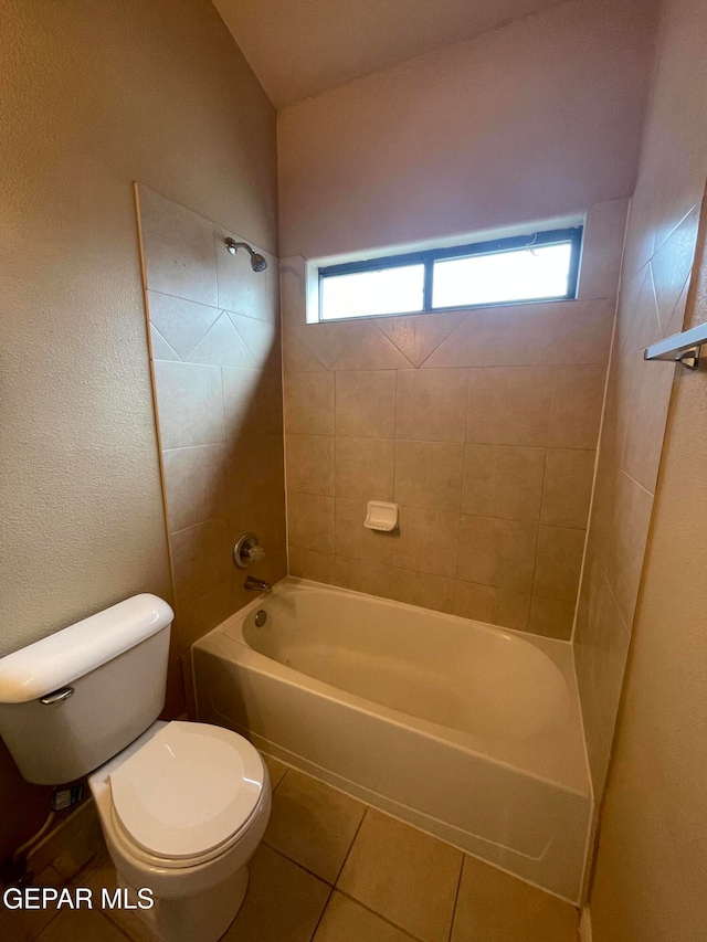 bathroom with tiled shower / bath, tile patterned floors, and toilet