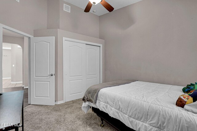 bedroom featuring light colored carpet, a closet, and ceiling fan