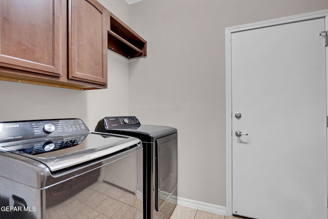 washroom featuring washer and dryer, cabinets, and light tile patterned floors