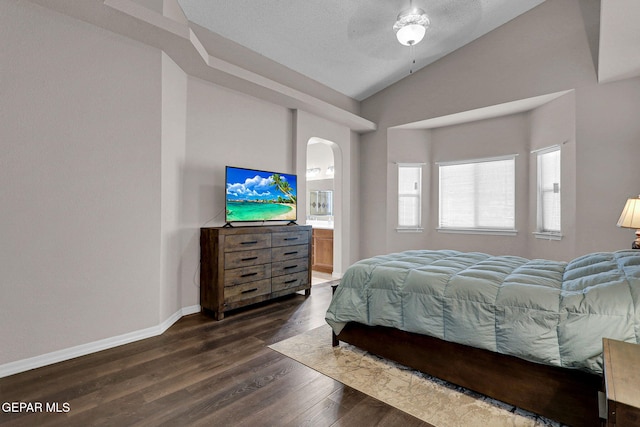 bedroom with a textured ceiling, dark hardwood / wood-style flooring, ceiling fan, vaulted ceiling, and connected bathroom