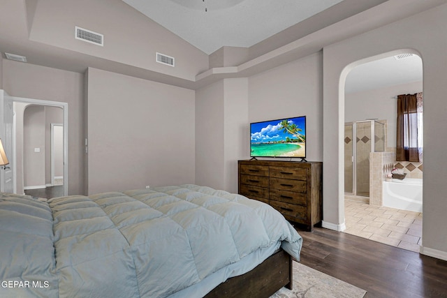 bedroom featuring dark wood-type flooring, ensuite bathroom, and vaulted ceiling