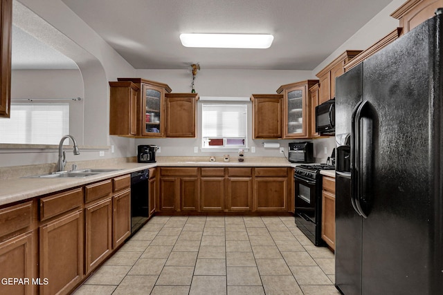 kitchen featuring sink, black appliances, light tile patterned flooring, and a textured ceiling