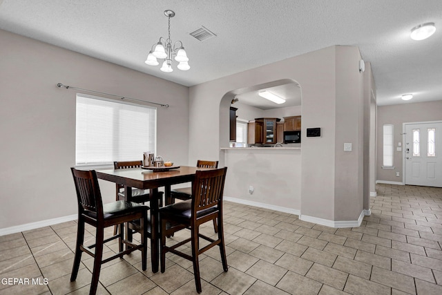 dining area featuring a notable chandelier, a textured ceiling, and a healthy amount of sunlight