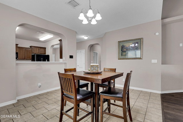 dining space featuring a textured ceiling, an inviting chandelier, and light wood-type flooring