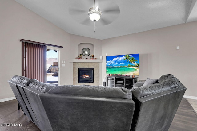 living room with ceiling fan, vaulted ceiling, a tile fireplace, and dark hardwood / wood-style floors