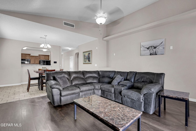 living room featuring lofted ceiling, wood-type flooring, and ceiling fan with notable chandelier