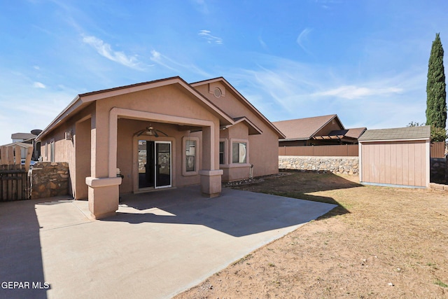 back of property with a storage unit, a patio area, and ceiling fan