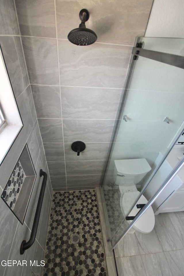 bathroom featuring a tile shower and toilet