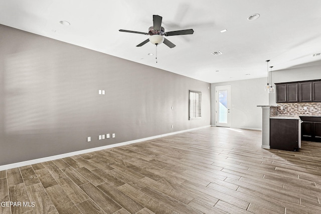 unfurnished living room featuring ceiling fan with notable chandelier, sink, and wood-type flooring