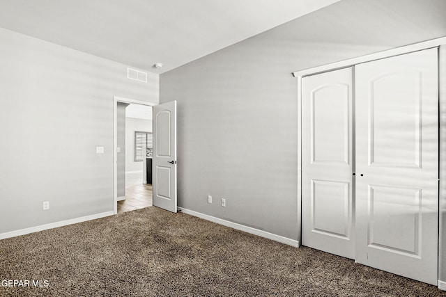 unfurnished bedroom with dark colored carpet and a closet