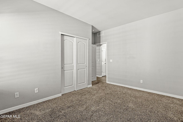 unfurnished bedroom featuring dark carpet and a closet