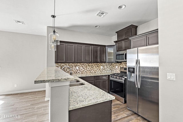 kitchen featuring stainless steel appliances, kitchen peninsula, decorative light fixtures, and light hardwood / wood-style flooring