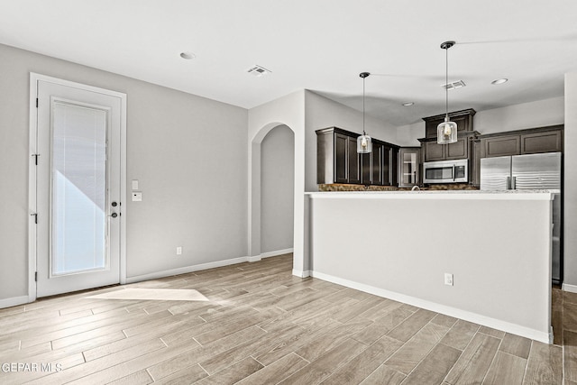 kitchen with dark brown cabinets, light hardwood / wood-style floors, hanging light fixtures, and stainless steel appliances