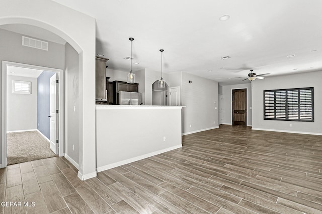 kitchen with ceiling fan, pendant lighting, stainless steel refrigerator, and dark wood-type flooring