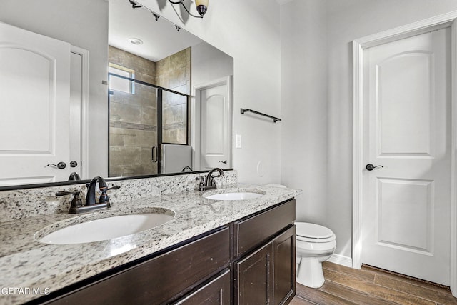 bathroom featuring toilet, hardwood / wood-style flooring, vanity, and an enclosed shower